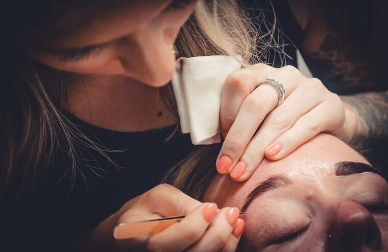 Kyndal shaping a client's brows with tweezers